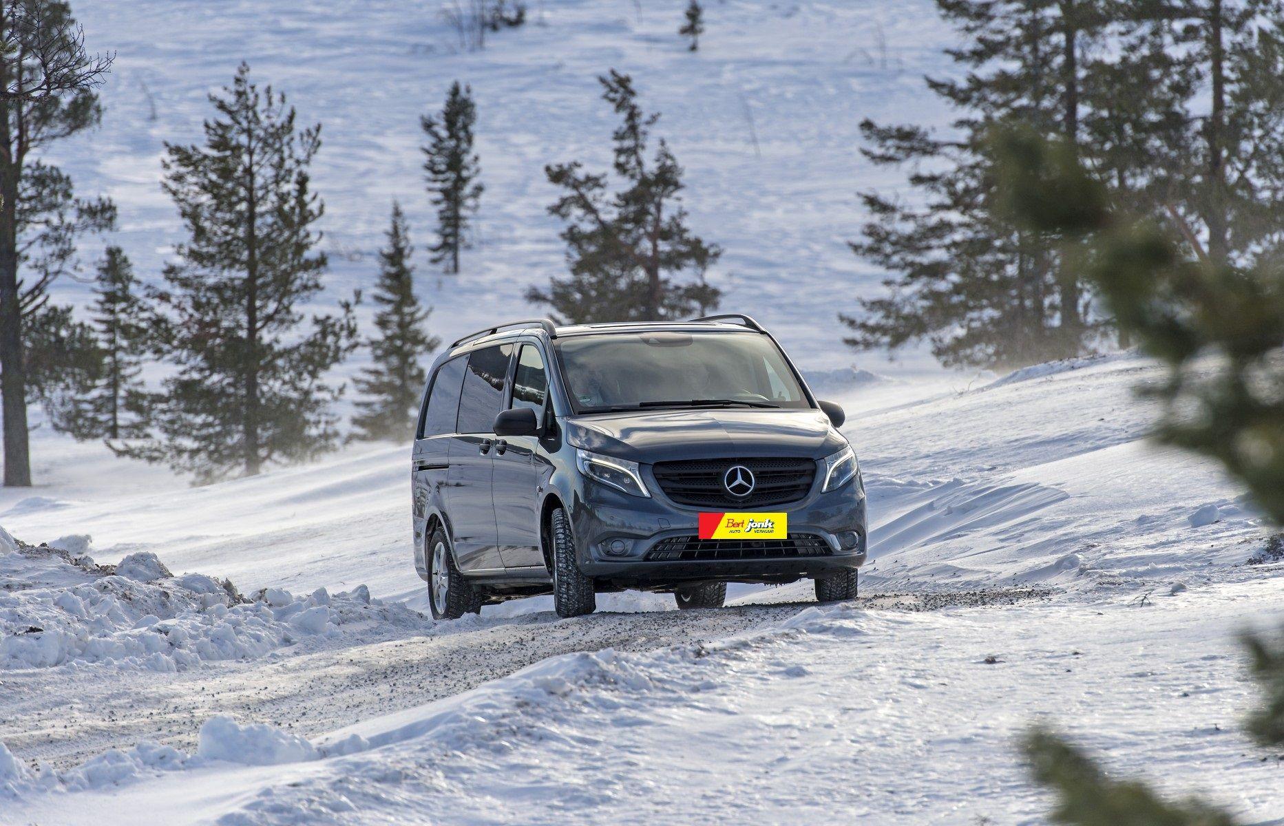Witte Mercedes Vito personenbus rijdt door een besneeuwd winterlandschap